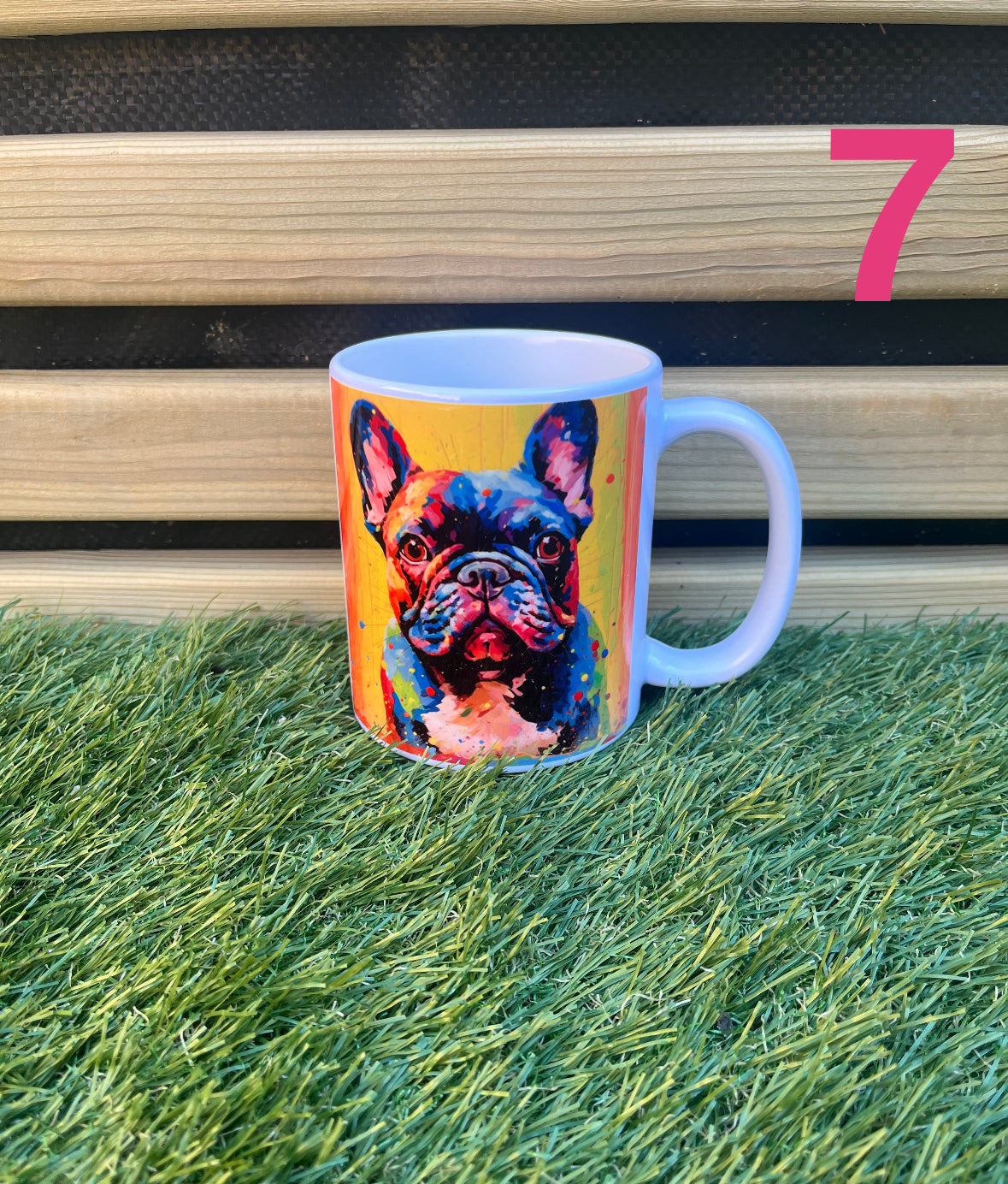 Mug with a colorful dog design on grass with a wooden bench in the background