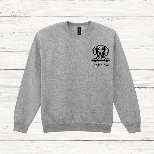 Gray sweatshirt with a dog illustration and text on a wooden surface