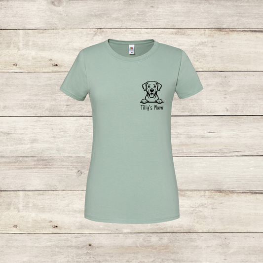 Light green t-shirt with a dog illustration and text on a wooden surface