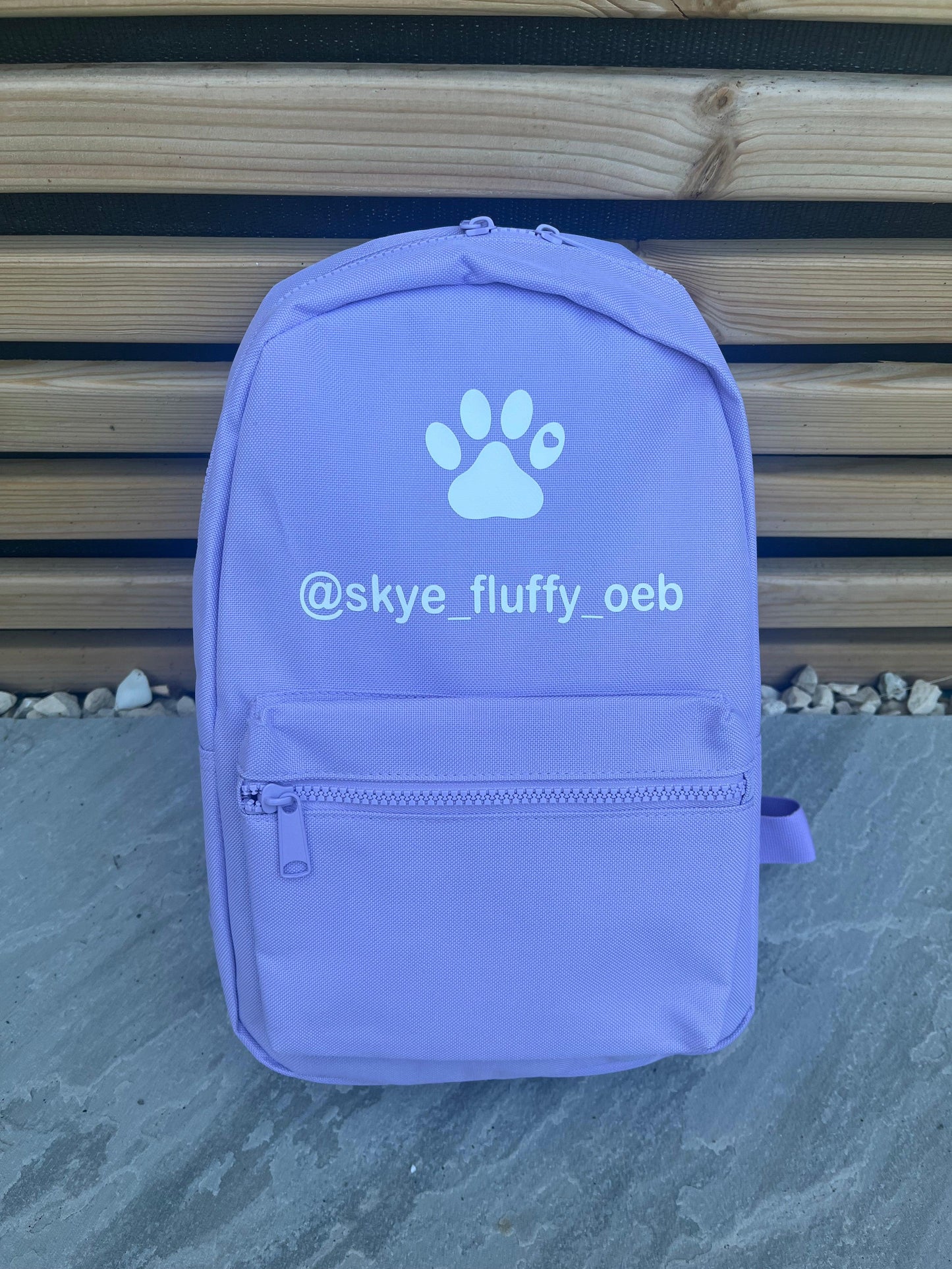 Purple backpack with a paw print and text on a wooden background