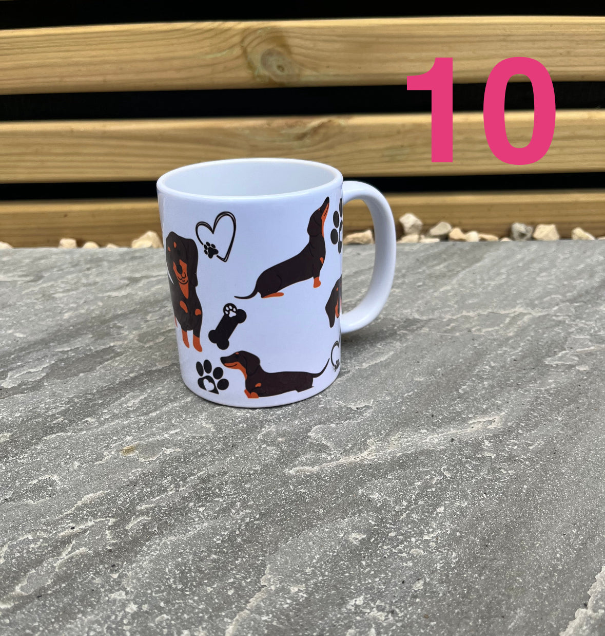 White mug with dachshund illustrations on a stone surface with wooden background