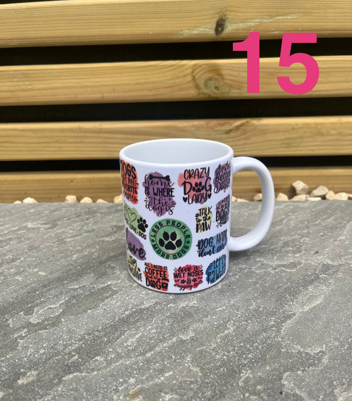 White mug with colorful text and paw prints on a stone surface with wooden background