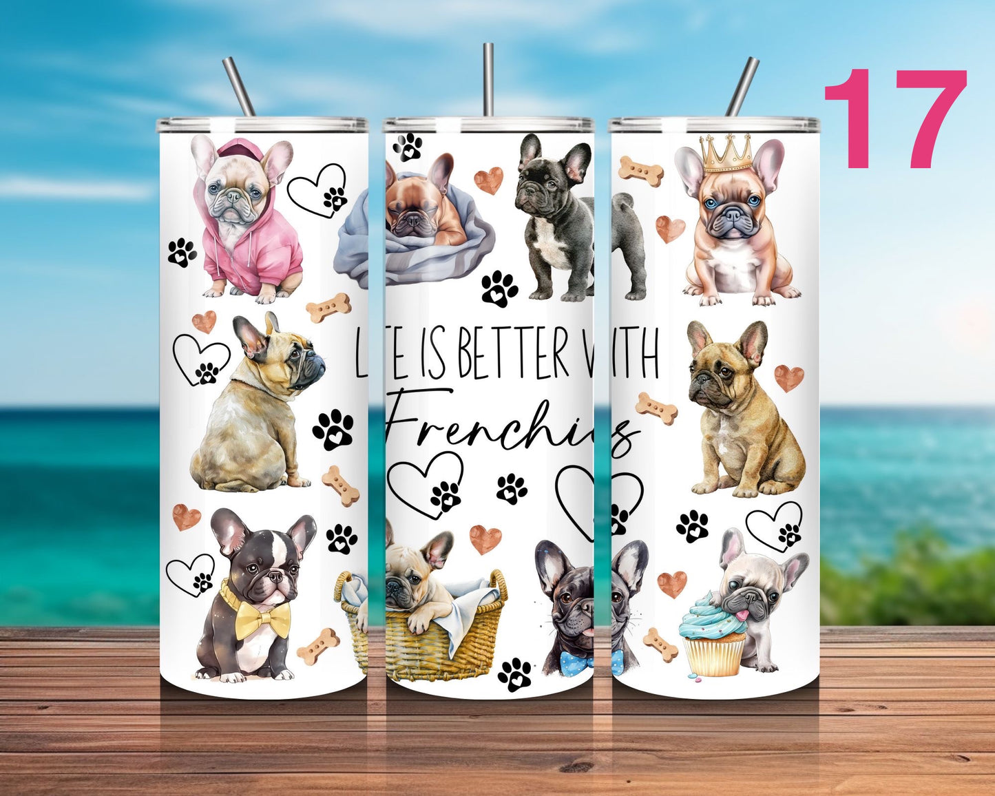 Three tumblers with French Bulldog designs on a wooden surface with a scenic background.