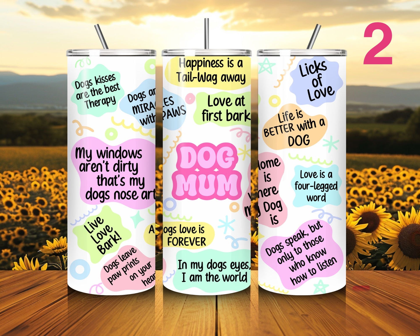 Three tumblers with dog-themed sayings on a wooden surface with a sunflower field background.