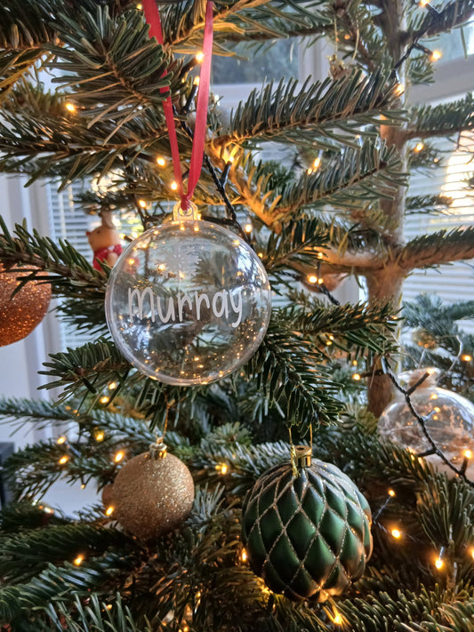 Personalised Christmas pet treat bauble hanging near a dog with festive decorations
