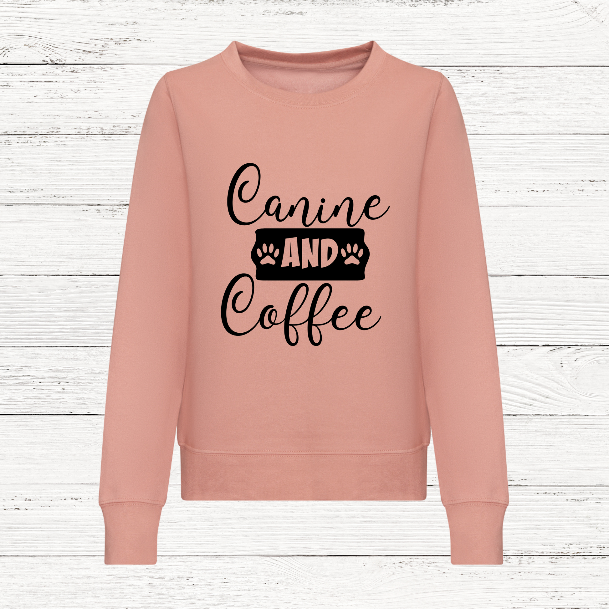 Pink sweatshirt with 'Canine and Coffee' text on a wooden background