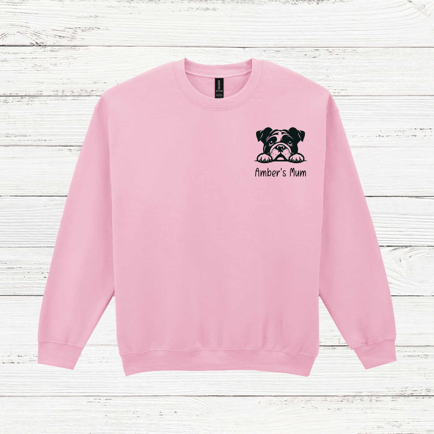Pink sweatshirt with a bulldog graphic and text on a wooden surface