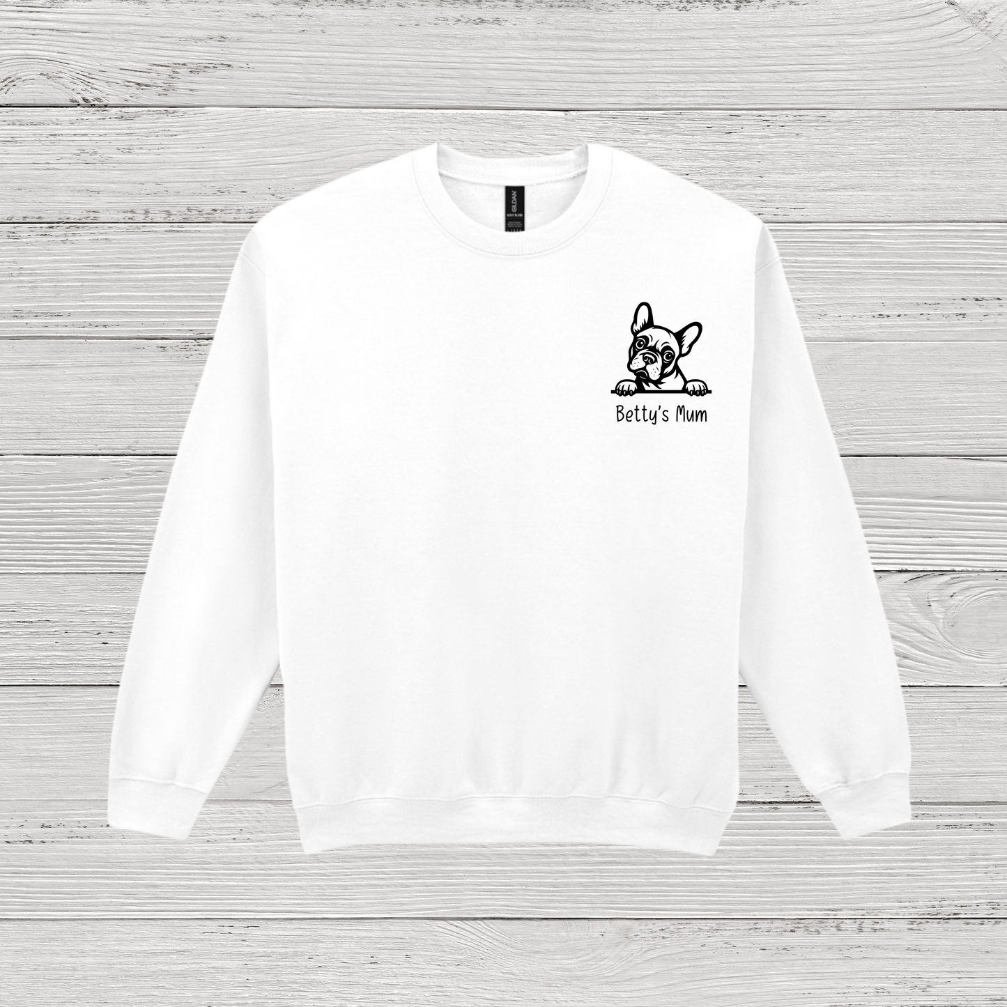White sweatshirt with a black dog illustration and text on a wooden surface