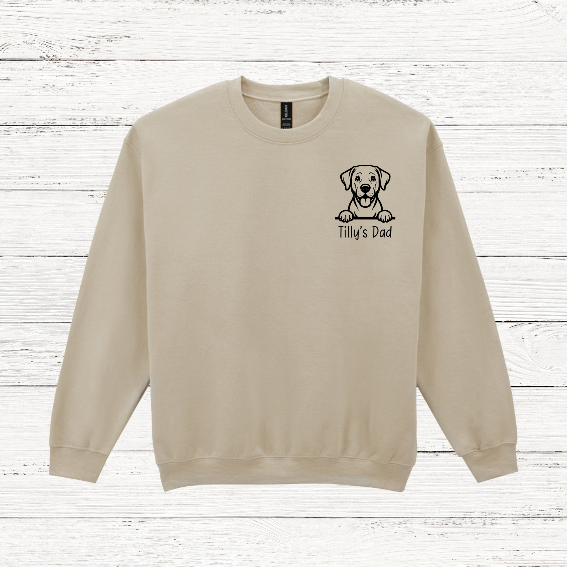 Beige sweatshirt with a dog illustration and text on a wooden surface