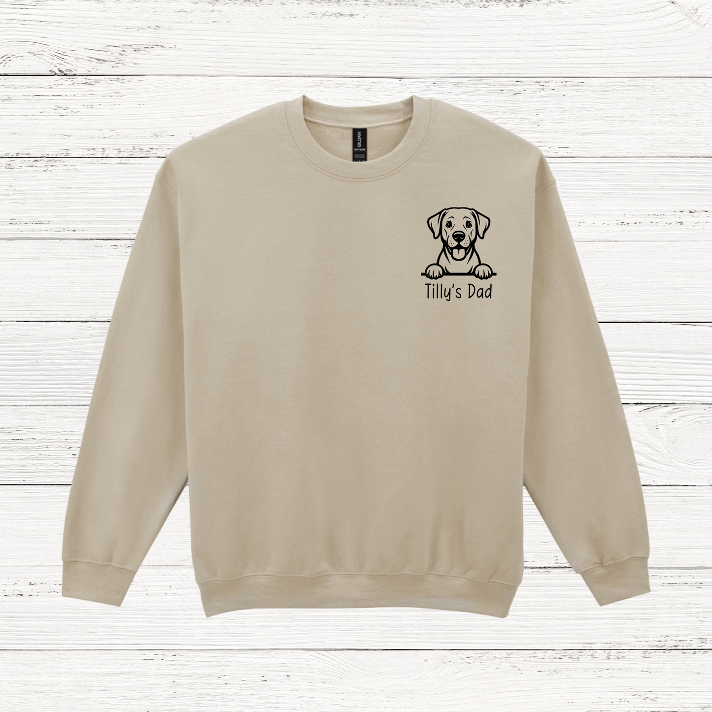 Beige sweatshirt with a dog illustration and text on a wooden surface