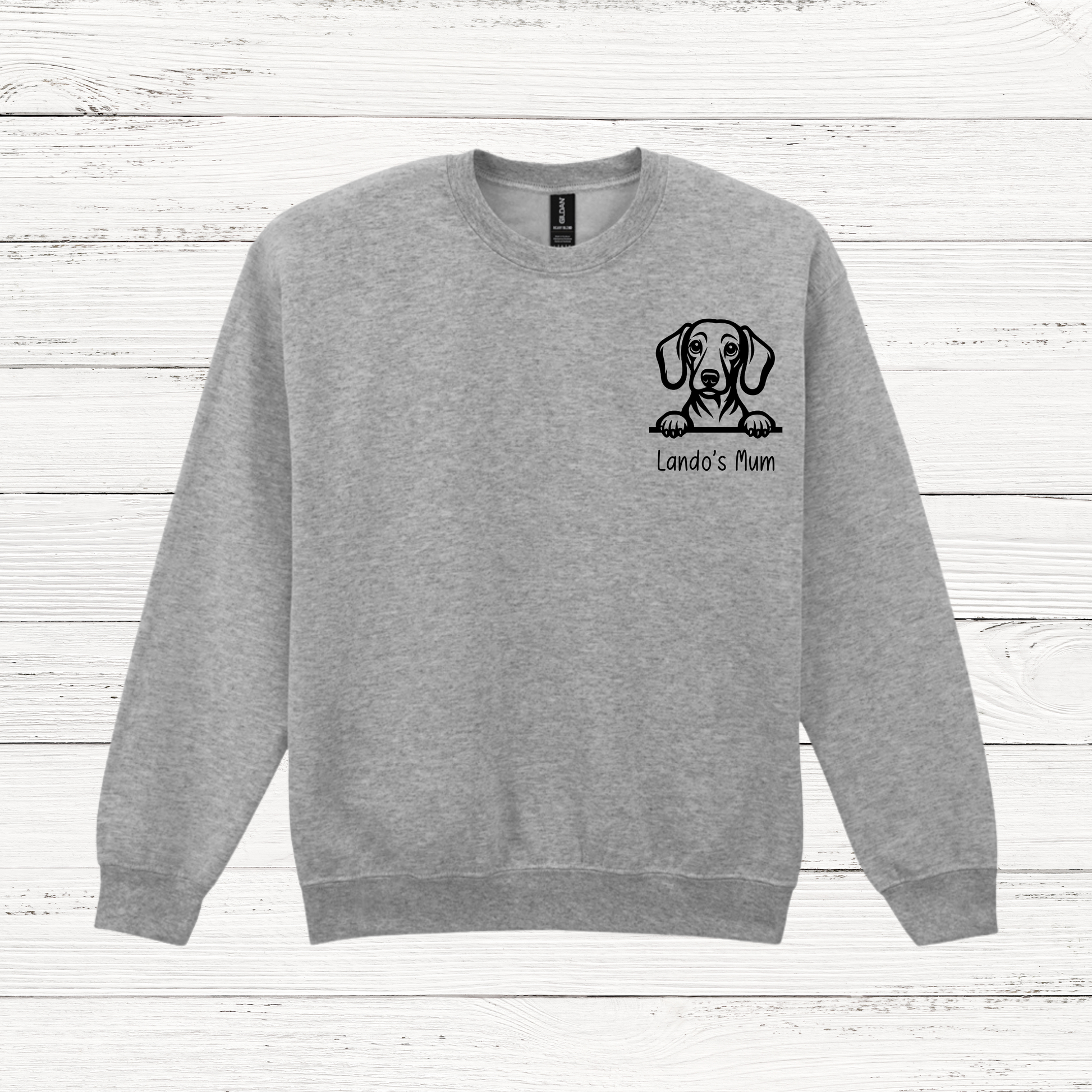 Gray sweatshirt with a dog illustration and text on a wooden surface