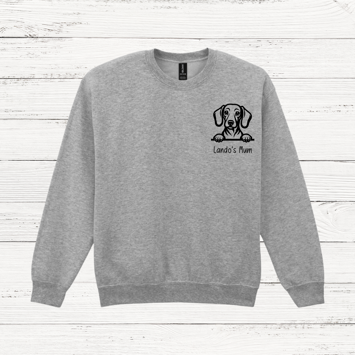 Gray sweatshirt with a dog illustration and text on a wooden surface