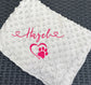 light grey textured blanket with pink text and heart design on a dark woven surface