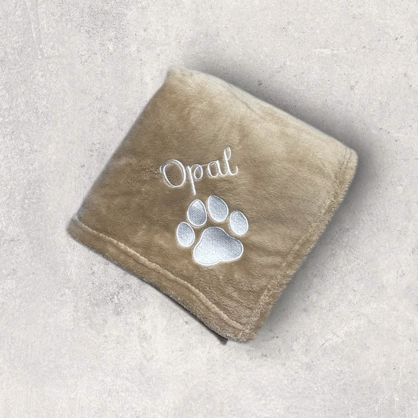 Brown towel with 'Opal' and paw print on a light gray background