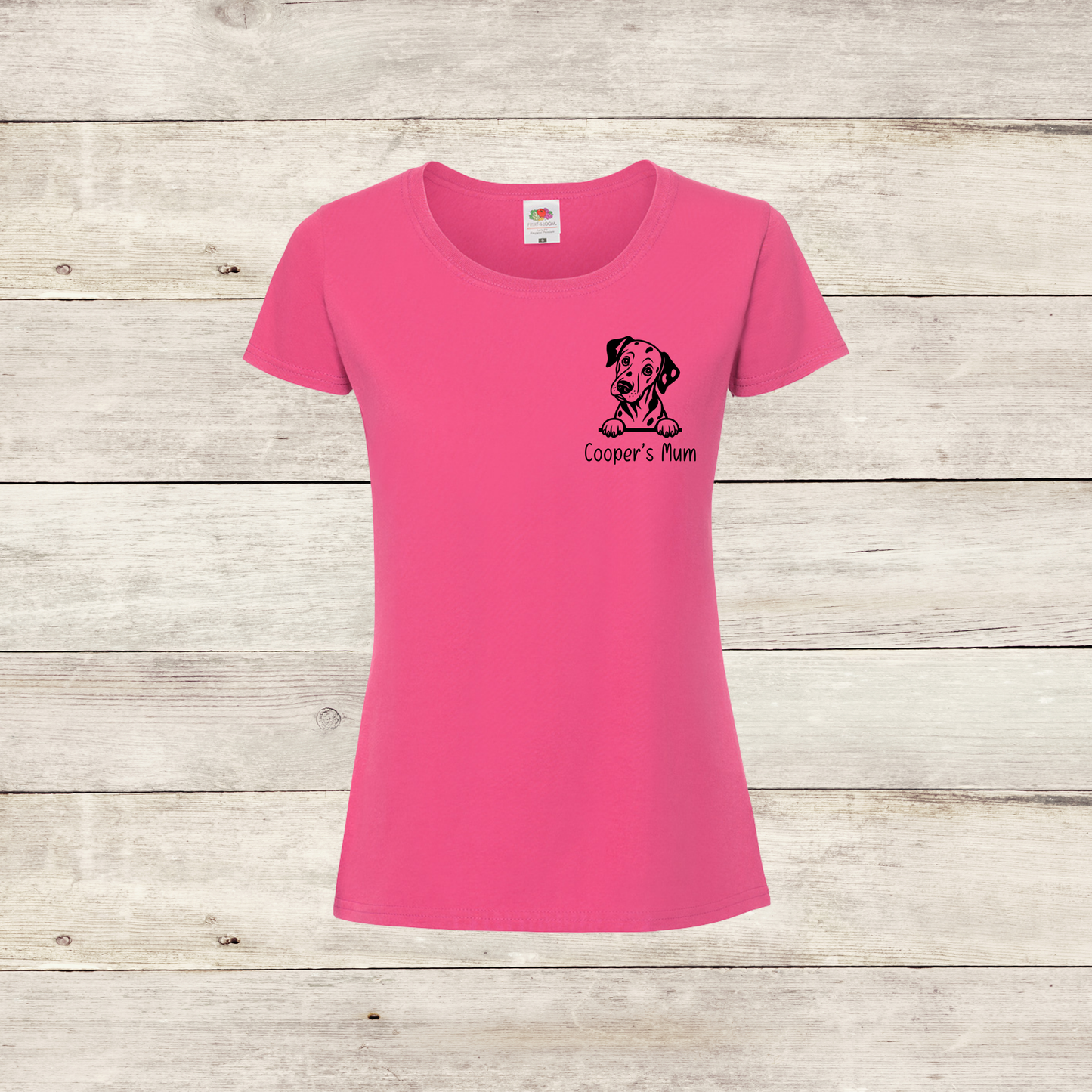 Pink t-shirt with a dog graphic and text on a wooden surface