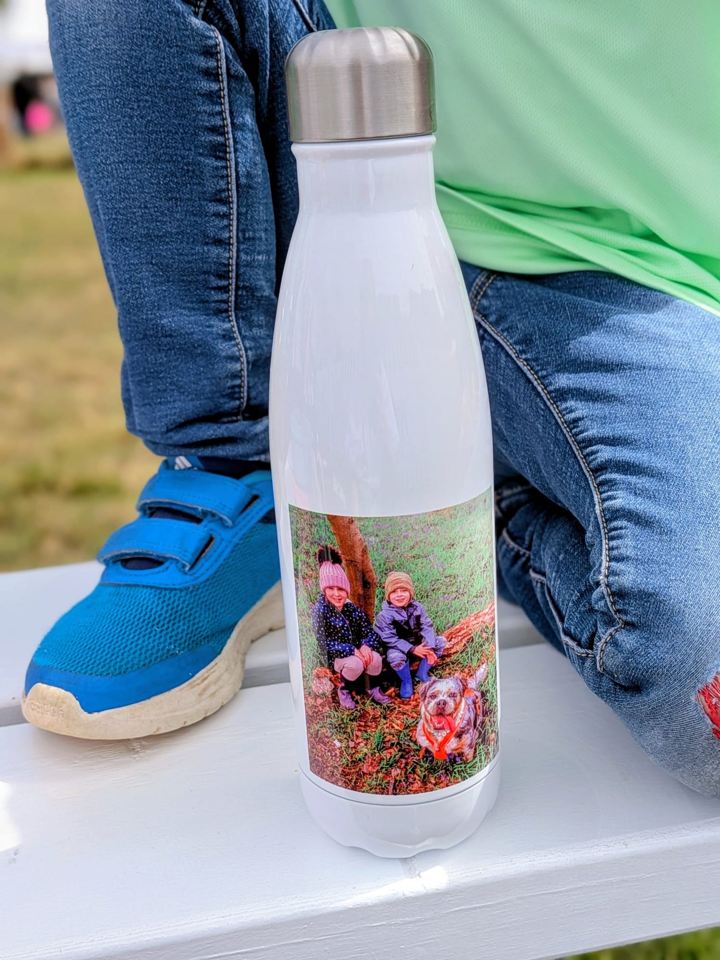 White water bottle with a photo of two children and a dog on a grassy field.