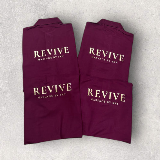 Folded maroon towels with 'REVIVE Massage by Sky' text on a light gray background