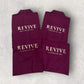 Folded maroon towels with 'REVIVE Massage by Sky' text on a light gray background