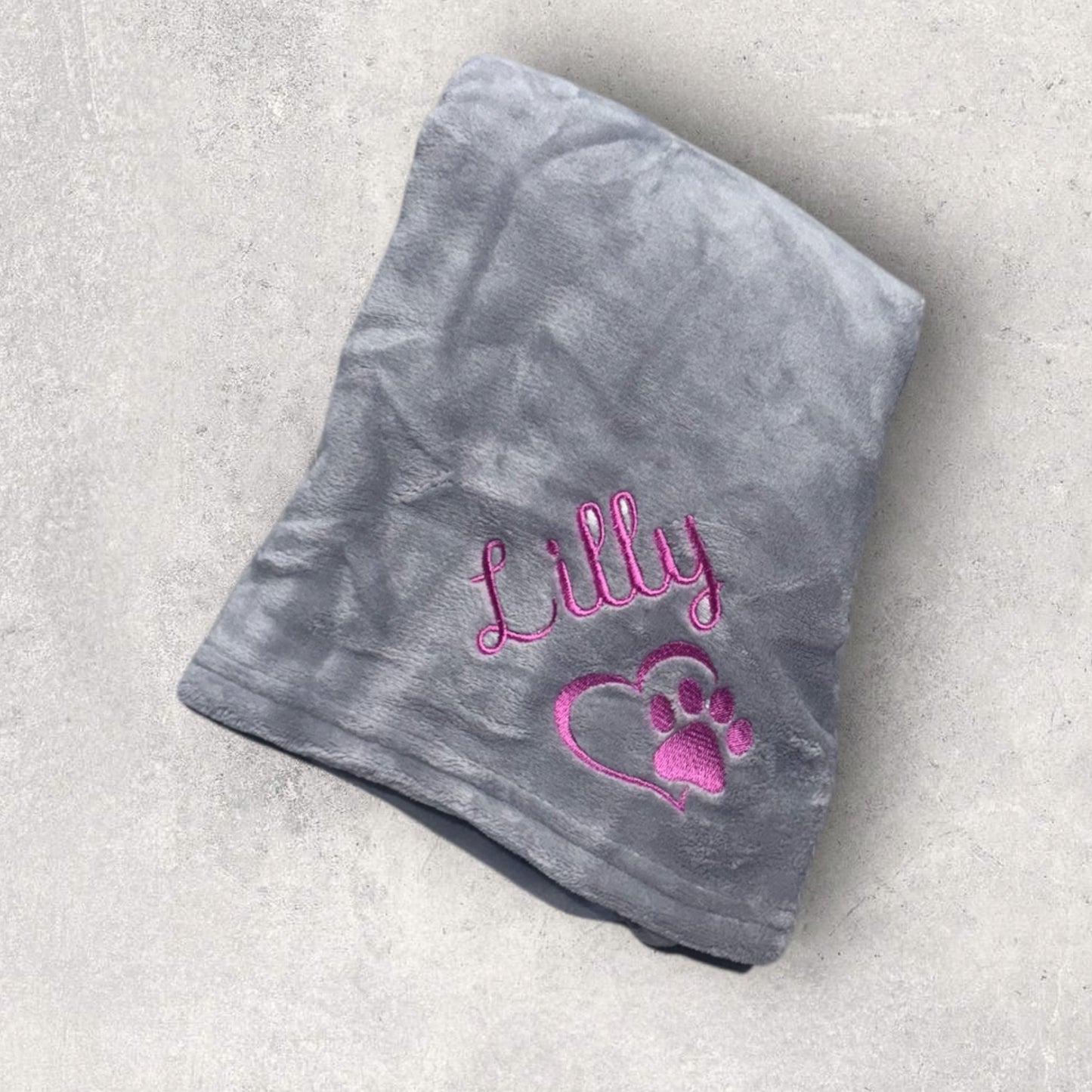 Gray blanket with pink text and heart design on a light gray background