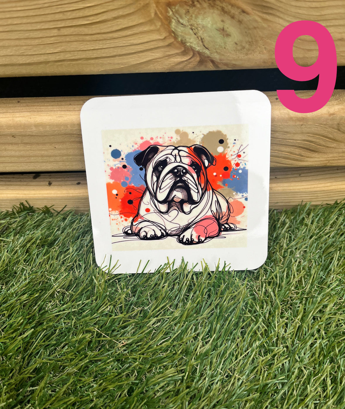 Coaster with a bulldog design on grass next to wooden planks
