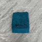 Teal towel with 'Mucky Pup' logo on a gray marble surface