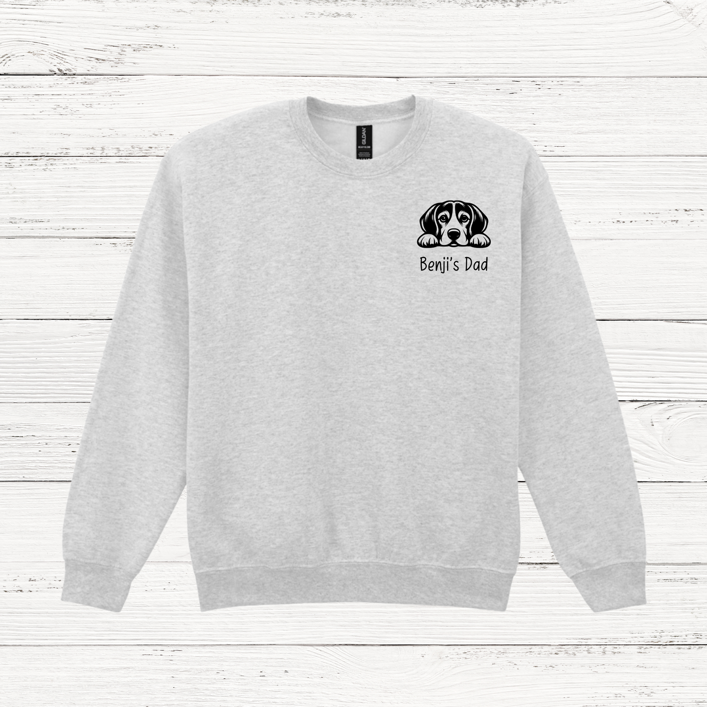 Gray sweatshirt with a dog graphic and text on a white wooden background