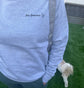 Person wearing a light blue sweatshirt with 'Dog Grandma' text, standing on grass with a dog.