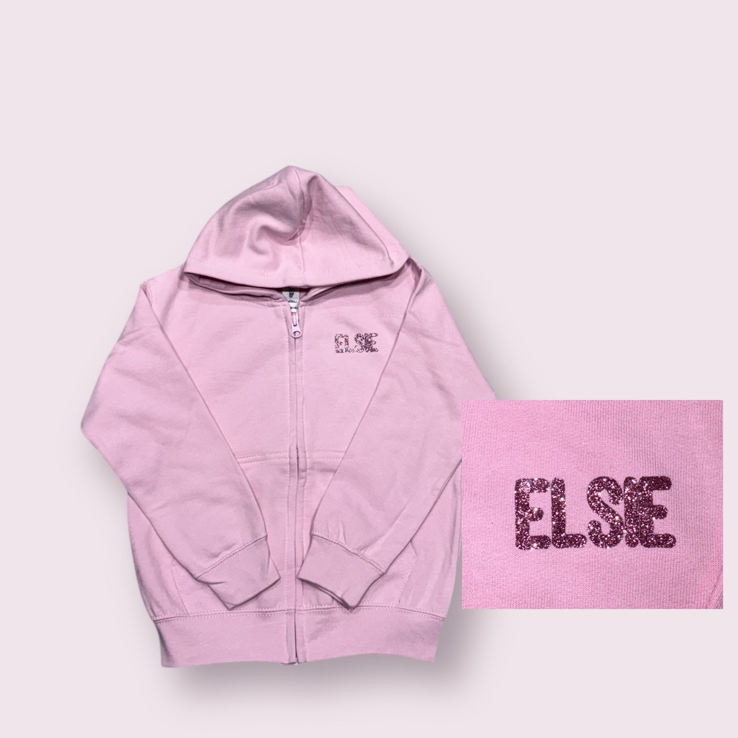 Pink hoodie and matching towel with 'ELSIE' branding on a light gray background