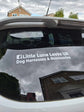 Car window with 'Little Luna Loves UK' decal reflecting a house and sky