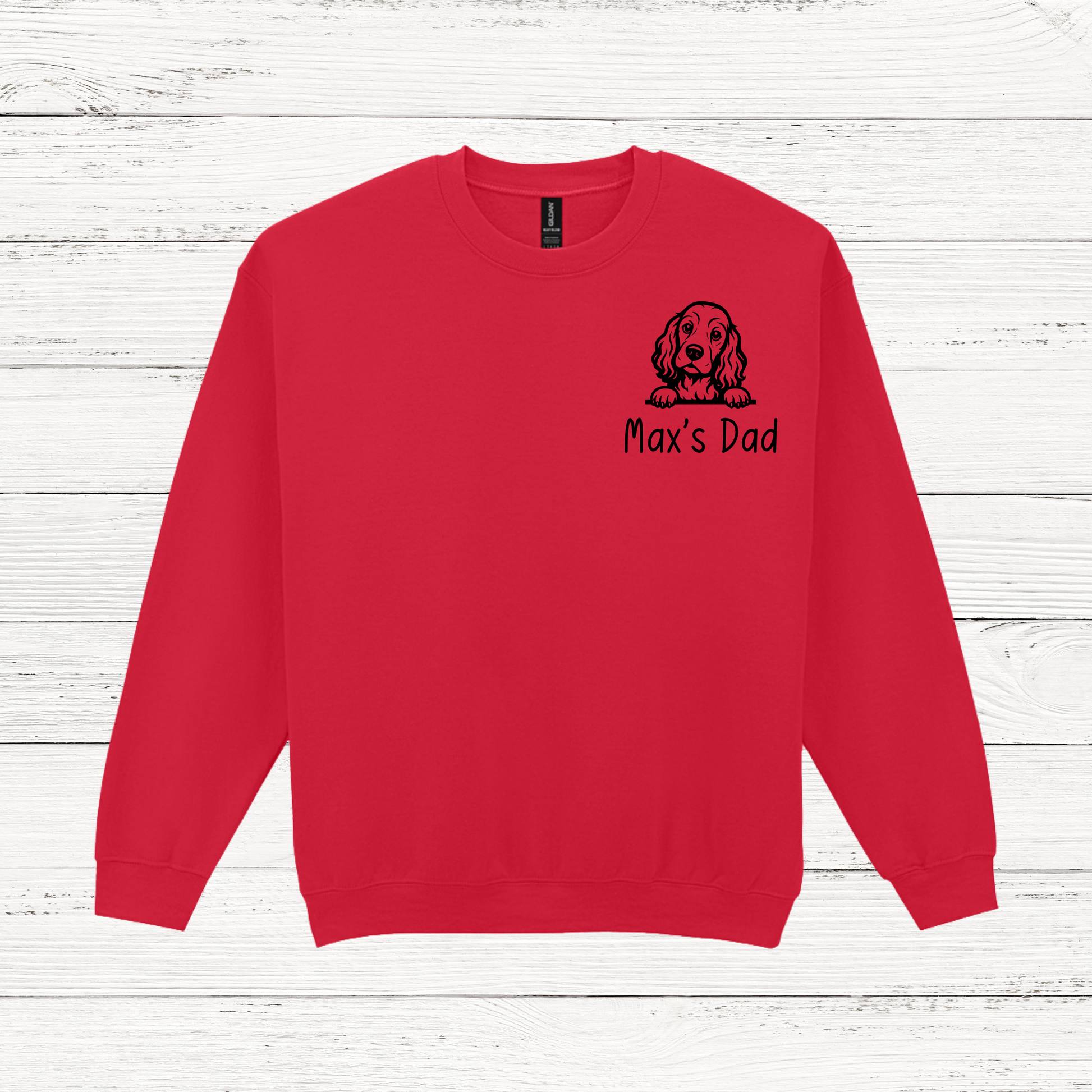 Red sweatshirt with a dog illustration and 'Max's Dad' text on a white wooden background
