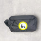 Black waits bag with a circular logo featuring a silhouette of a person and a dog on a light gray background