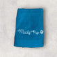 Blue towel with 'Mucky Pup' text on a textured gray background