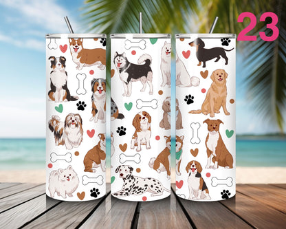 Three tumblers with dog pattern designs on a wooden surface with a beach background.