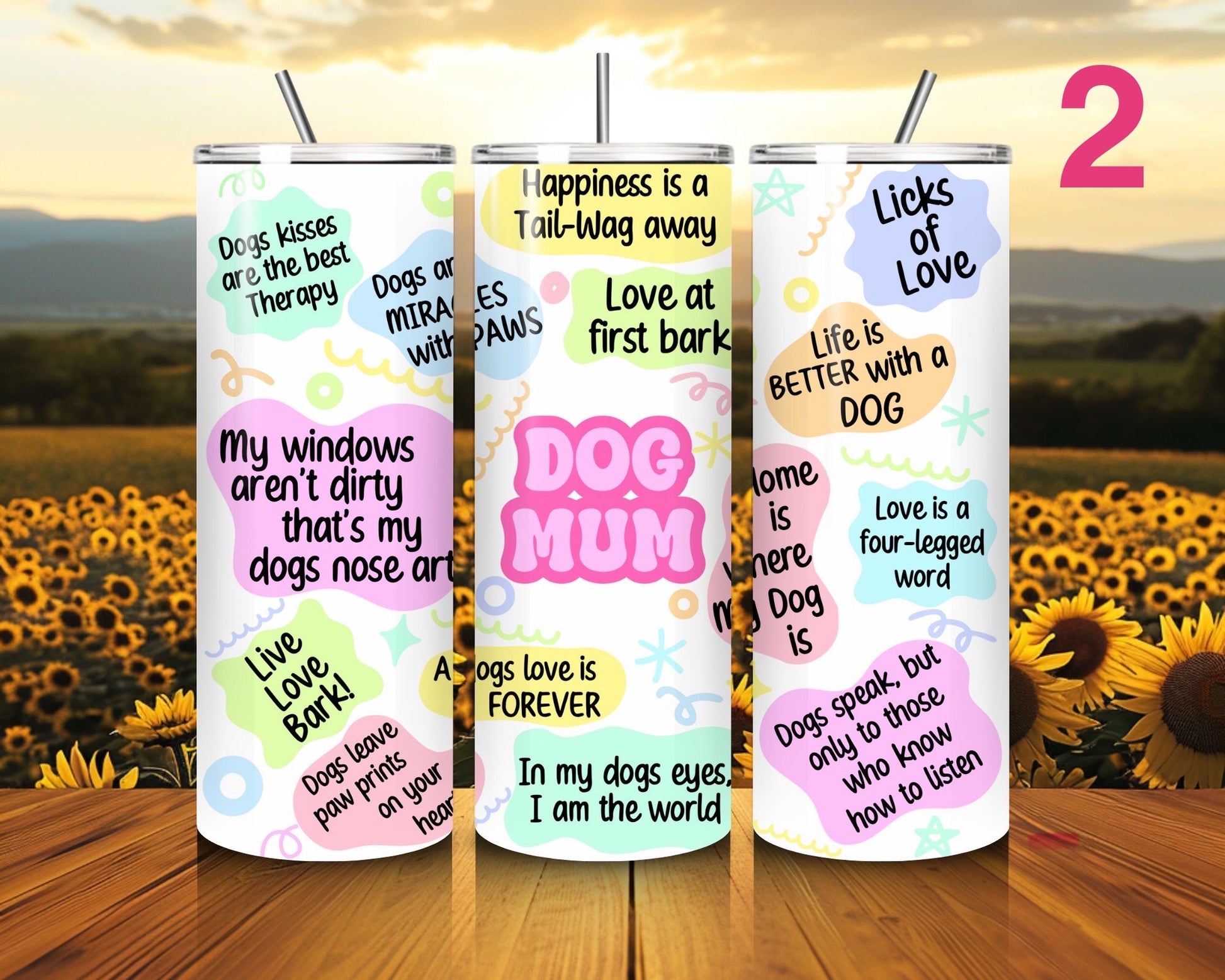 Three tumblers with dog-themed sayings on a wooden surface with a sunflower field background.