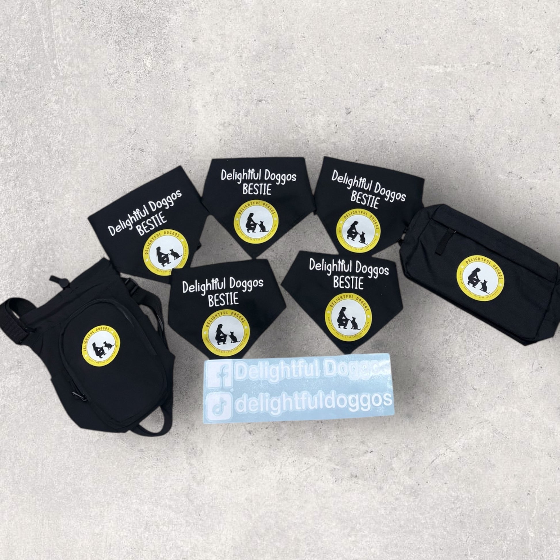 Set of black dog bandanas with 'Delightful Doggos Bestie' labels on a gray surface