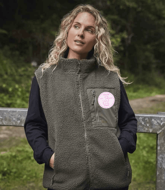 Woman wearing a green fleece gilet with a logo in a natural setting