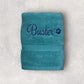 Teal towel with 'Buster' embroidered on a light gray background