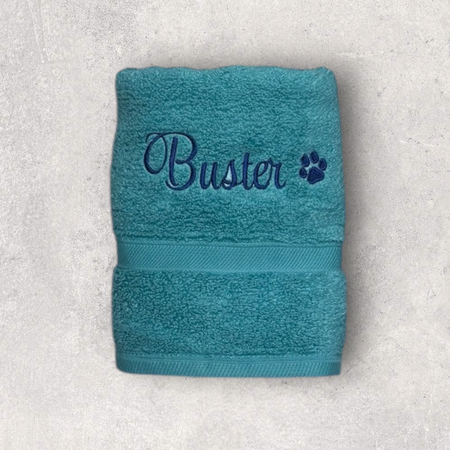 Teal towel with 'Buster' embroidered on a light gray background