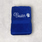 Folded blue towel with 'Buster' and a paw print on a light gray background