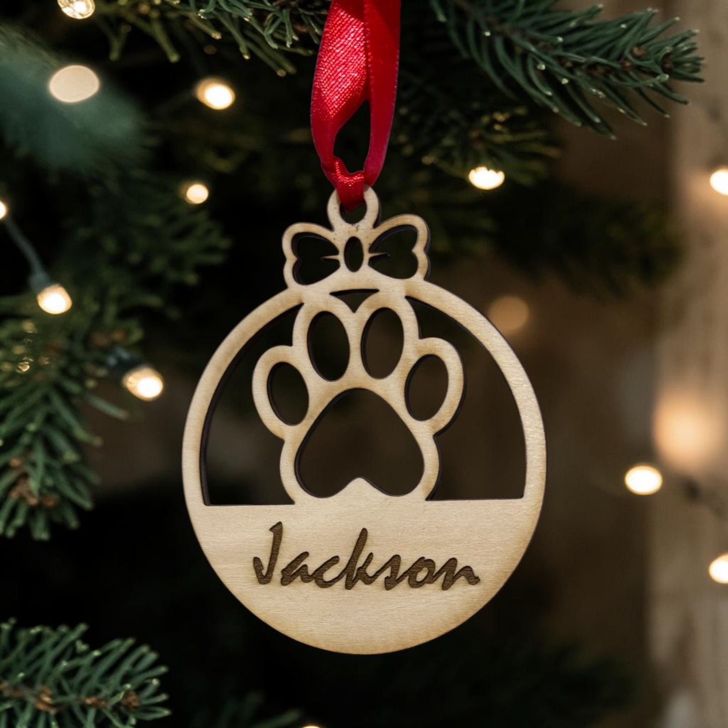 Personalised wooden Christmas bauble engraved with a pet's name hanging on a Christmas tree.